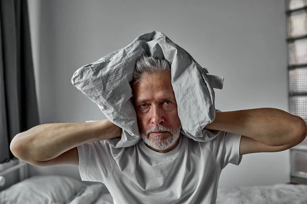 Senior homme devient fou avec l'insomnie, couvre ses oreilles avec un oreiller — Photo