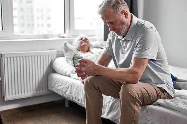 Anciana enferma con su cuidado marido anciano sentado cerca de ella — Foto de Stock
