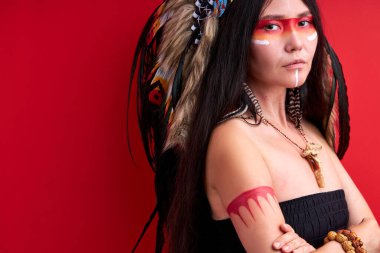 Kırmızı arka planda çapraz kolları olan harika bir Hint modeli duruyor.