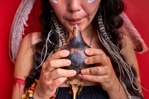 Przycięty szaman kobieta za pomocą autentyczne gwizdek indyjski izolowane na czerwonym tle — Zdjęcie stockowe