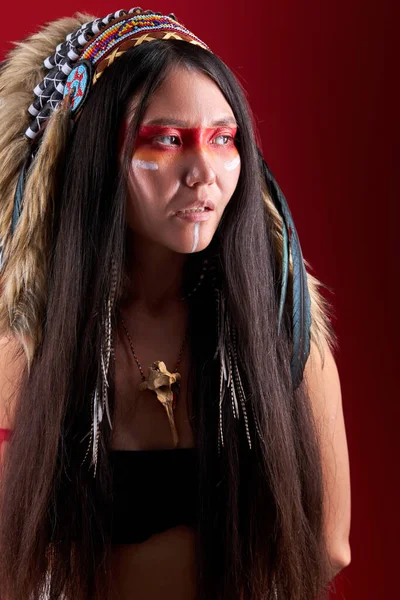 Mysterieuze indiaanse sjamaan vrouw met Indiase veer dragen en kleurrijke make-up kijk weg — Stockfoto