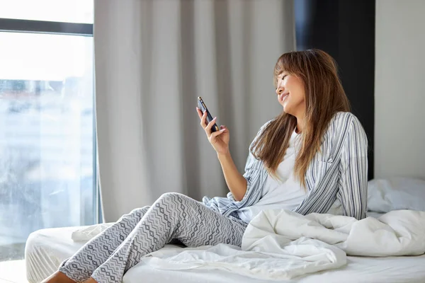 Улыбающаяся женщина в домашней одежде сидит в чате с парнем на кровати — стоковое фото