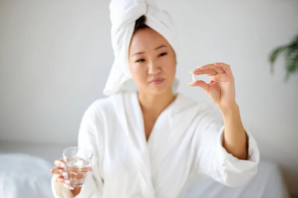 Hermosa joven asiática mujer a punto de tomar una tableta, sosteniendo píldoras en las manos — Foto de Stock
