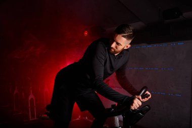 Sporcu erkek spor salonunda antrenman yapıyor, arkasına bakıyor.