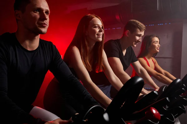 Pessoas fitness andar de bicicleta na aula de fiação no ginásio moderno — Fotografia de Stock