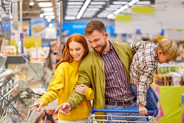 Vrolijke familie met rusteloze grappige zoon in supermarkt — Stockfoto