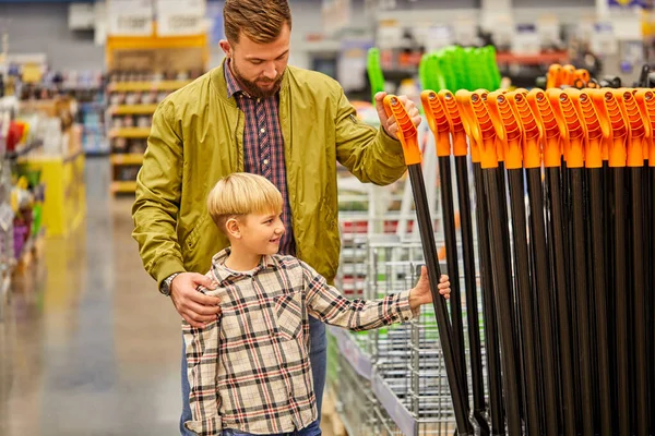 これを持って行こう。子供の男の子と男は店でシャベルを買って — ストック写真