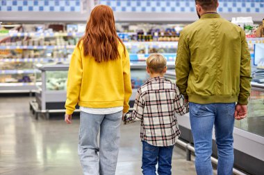 Çocuk alışverişi yapan arkadaş canlısı aile, el ele tutuşuyorlar.