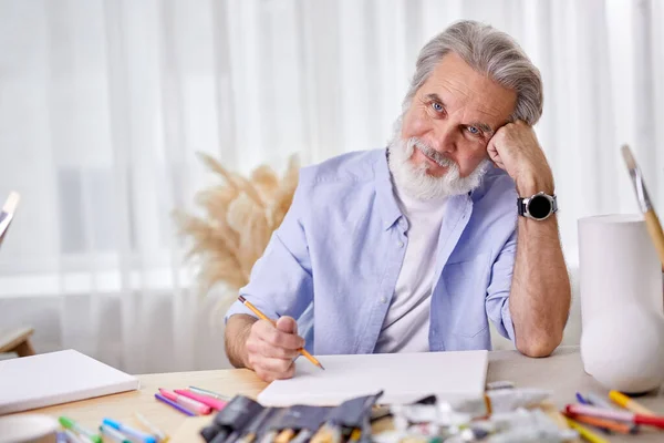 疲惫的高加索老年艺术家坐在桌子后面 — 图库照片
