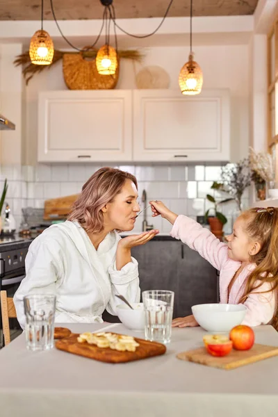 Joven mujer caucásica y niña desayunar en la cocina en casa — Foto de Stock