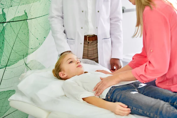 Sick child girl lie on bed in hospital, mom calms down her — Stok fotoğraf