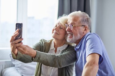 beautiful happy elderly couple taking photo on smartphone