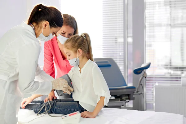 Professional doctor woman measuring blood pressure of girl using tonometer — Stok fotoğraf