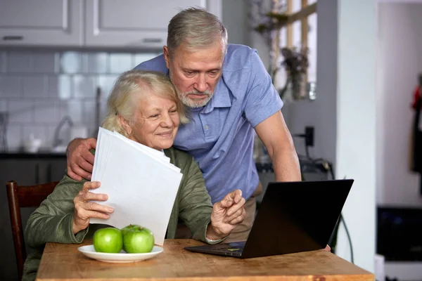 Worried senior couple checking finances at home using laptop — Fotografia de Stock
