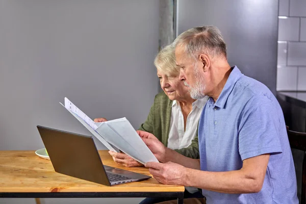 Worried senior couple checking finances at home using laptop — Φωτογραφία Αρχείου