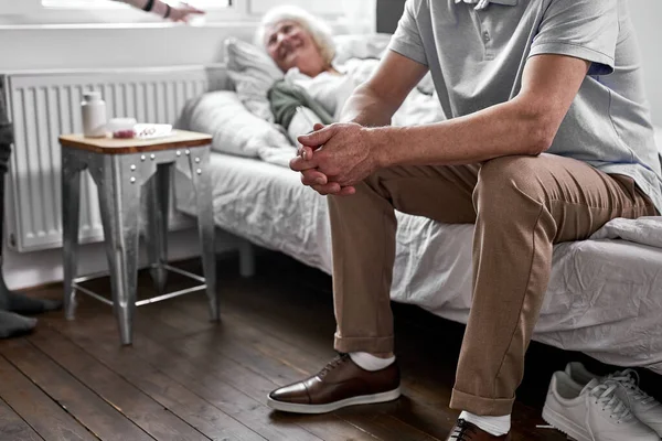 Homem deprimido senta-se perto de sua esposa doente — Fotografia de Stock