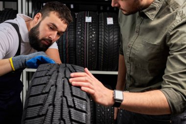 two men looking at auto tire surface
