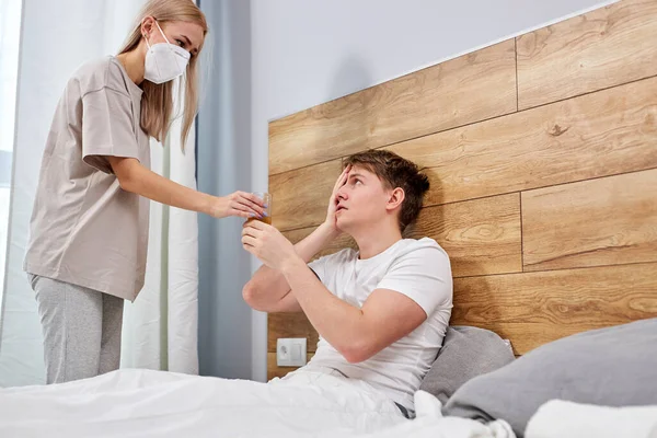 Sick caucasian young man having cold, lying on bed at home feeling unwell, with high temperature — Foto de Stock