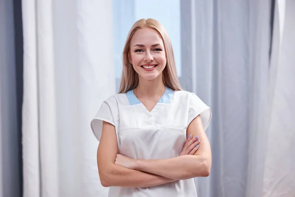 Positive young caucasian female nurse in white coat looking at camera — Foto de Stock