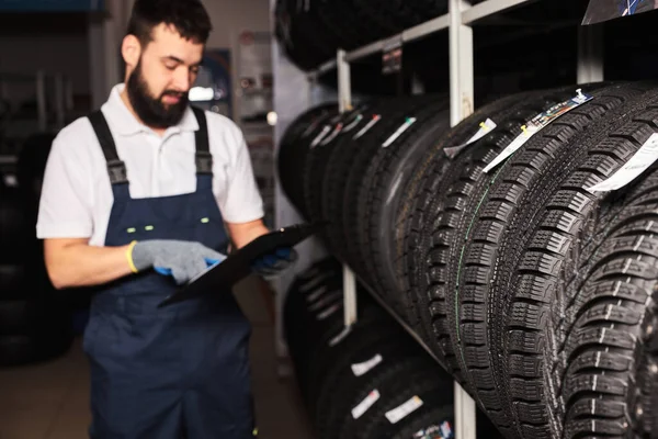 Confident meachanic man during work, focus on tires — Stockfoto