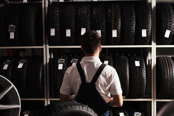 Rear view on young male mechanic with looking at car tires in automobile service center — Foto Stock