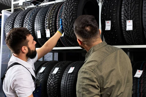 Mechaniker und Kunde sprechen in der Werkstatt über Reifen — Stockfoto