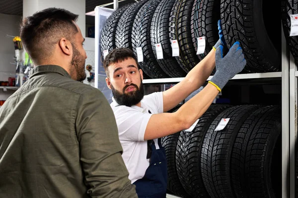 Vstřícný automechanik v uniformě pomoci zákazníkovi s výběrem — Stock fotografie
