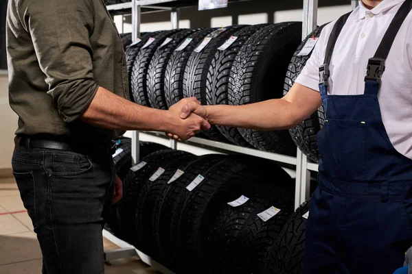 Salesman and customer shaking hands in auto service shop — Stok fotoğraf