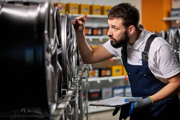 Confident male auto mechanic is checking car discs represented for sale in service — Stockfoto