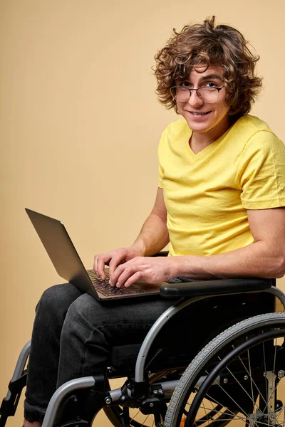 Positive disabled person in casual wear sitting with laptop — стоковое фото