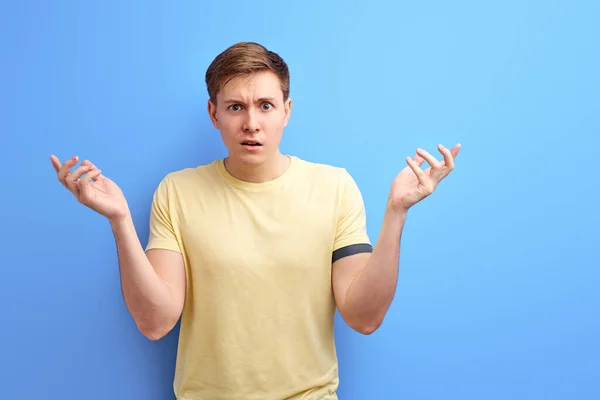 Joven guapo caucásico hombre usando casual camiseta de pie sobre aislado azul fondo despistado y confundido —  Fotos de Stock