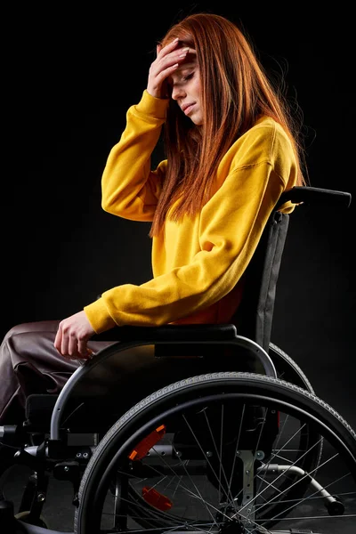 Μελαγχολική κοκκινομάλλα κάθεται σε αναπηρικό καροτσάκι δυστυχισμένη. — Φωτογραφία Αρχείου