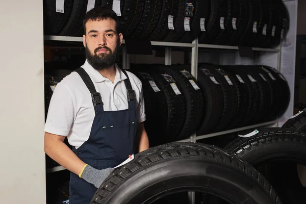 Caucasico maschio meccanico vicino rack con pneumatici auto in negozio di auto — Foto Stock