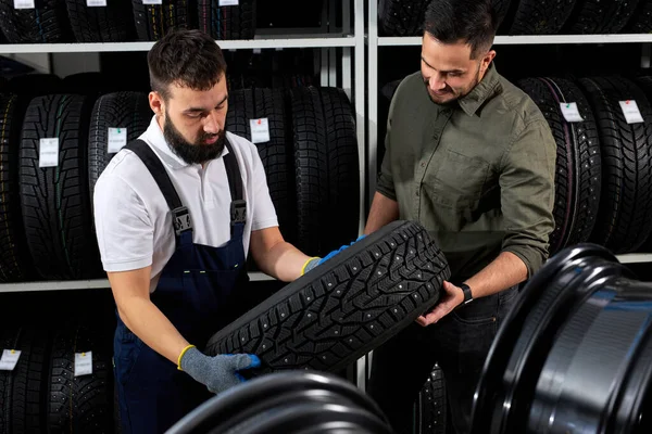 Meccanico e cliente parlando di pneumatici presso il garage di riparazione — Foto Stock