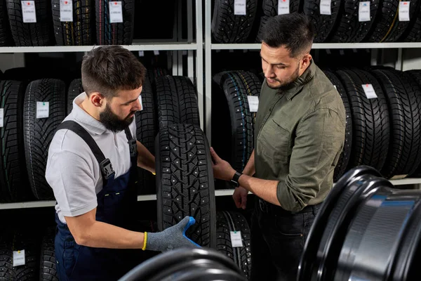 Mekaniker og kunde taler om dæk på reparation garage - Stock-foto