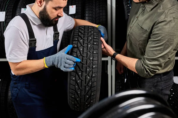 Kaukasischer Mechaniker hält einen Reifen in der Hand und zeigt Radreifen in Autowerkstätten und Autohäusern — Stockfoto