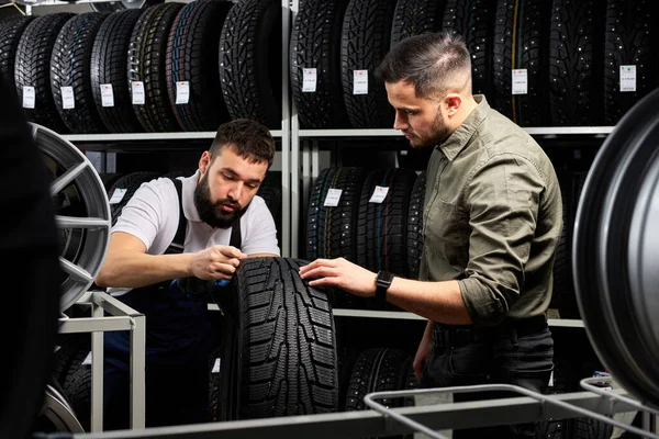 Meccanico auto parlare di vantaggi di pneumatico auto al giovane cliente in servizio — Foto Stock