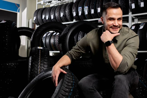 Ritratto di un cliente maschio circondato da molti pneumatici per auto — Foto Stock