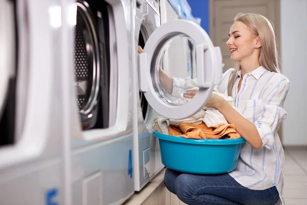 Caucasian woman doing the daily chores - laundry. Female folded clean clothes in the laundry basin