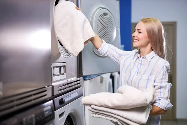 Красивая женщина загружает постельное белье в стиральную машину — стоковое фото