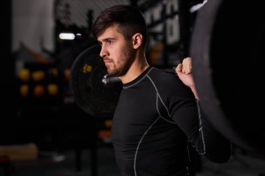 Halterli adam eğitimi. Erkek vücut geliştirici koyu renk spor salonunda ağırlık kaldırma egzersizi yapıyor.