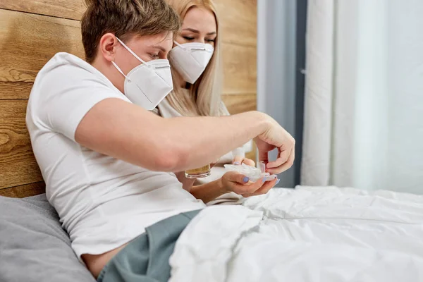 Hombre y mujer que toman vitaminas mientras están sentados en la cama sufriendo de COVID-19 —  Fotos de Stock