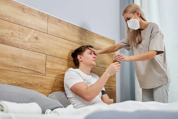 Worried wife take care his sick husband while she is sitting on a bed at home — Stock Photo, Image