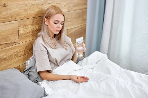 Mujer rubia linda sosteniendo píldoras tiempo para tomar medicamentos, cura para el dolor de cabeza —  Fotos de Stock