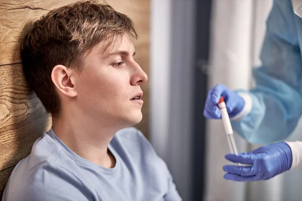 Médico recortado tomar hisopo nasal y garganta por paciente joven enfermo en casa — Foto de Stock