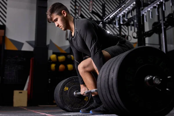 Sporcu, spor salonunda kaldırmaya hazırlanırken dizlerinin üzerinde duruyor. — Stok fotoğraf