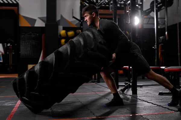 Ajuste atleta masculino caucásico haciendo ejercicio neumático-flip en interiores — Foto de Stock