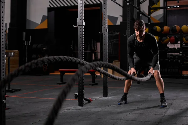 Jovem forte trabalhando com cordas de batalha no ginásio crossfit — Fotografia de Stock