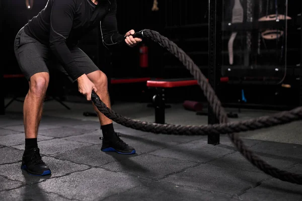 Cortado atlético jovem caucasiano fazendo exercícios crossfit com corda no ginásio — Fotografia de Stock