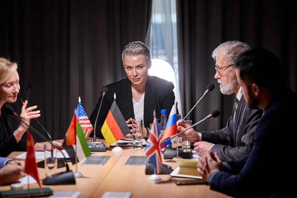 Grupp politiska ledare som sitter med mikrofoner vid presskonferensen — Stockfoto